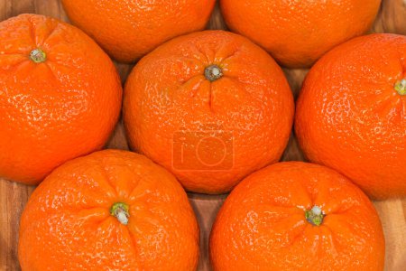 Foto de Whole ripe tangerines Murcott, also known as honey tangerines on the wooden dish, fragment, top view close-up - Imagen libre de derechos