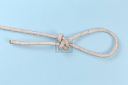 Foto de Nudo tridente de cuerda apretada sobre fondo azul - Imagen libre de derechos