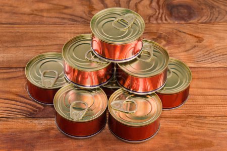 Heap of the small round sealed tin cans of a canned fish with easily opened lids on a rustic table