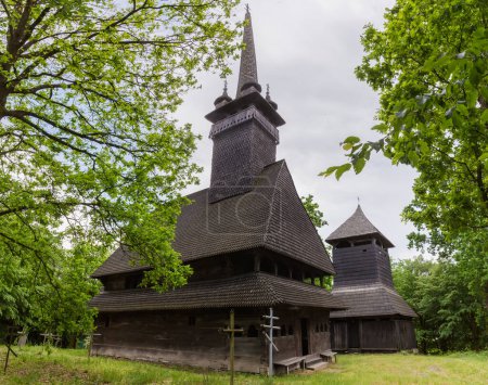 Photo for Gothic two-log wooden Church of the St. Nicholas the Wonderworker of 18th century and wooden bell tower in the Danylovo village, Ukraine - Royalty Free Image