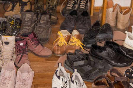 Téléchargez les photos : Empilés de la vieille varicolore diverses chaussures pour hommes et femmes usés pour différentes saisons, fragmenter le gros plan en mise au point sélective - en image libre de droit
