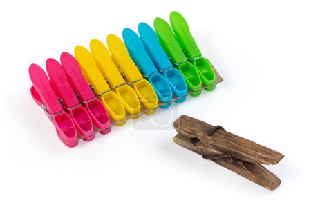 Photo for Old dark wooden clothespin over against the set of the modern new multi-colored spring-type plastic clothespins on a white background - Royalty Free Image