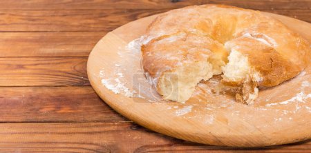 Téléchargez les photos : Lavash épais cuit au four avec une pièce arrachée sur une planche saupoudrée de farine située à droite sur une table rustique, vue panoramique - en image libre de droit