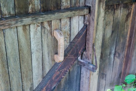 Photo for Fragment of the old plank wicket darkened by time with wooden handle and antiquated wooden door latch with steel spring - Royalty Free Image
