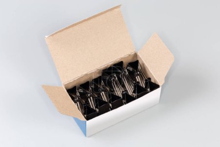 Photo for Black binder clips for paper packed in the open paperboard box on a gray background - Royalty Free Image