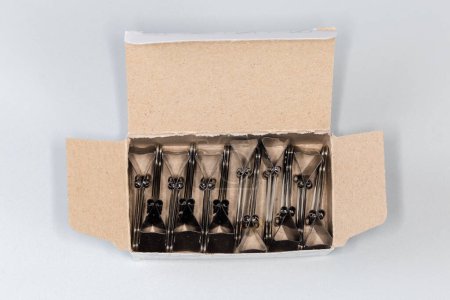 Photo for Black binder clips for paper packed in the open paperboard box, top view on a gray background - Royalty Free Image