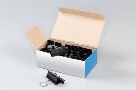 Photo for Set of the binder clips for paper packed in the open paperboard box on a gray background - Royalty Free Image
