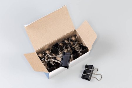 Photo for Set of the binder clips for paper packed in the open paperboard box on a gray background - Royalty Free Image