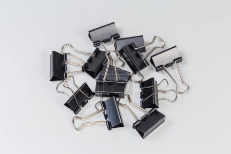Photo for Small heap of the black binder clips for paper on a gray surface - Royalty Free Image