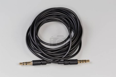 Photo for Rolled up analog audio cable with gold-plated stereo connectors mini jack on the edges on a gray surface - Royalty Free Image
