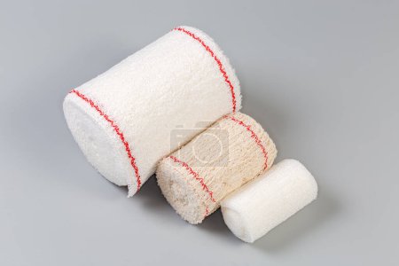 Photo for Three modern woven elastic medical bandages different sizes rolled into rolls on a gray background - Royalty Free Image