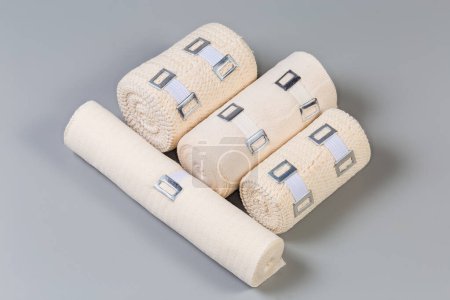 Photo for Several modern woven elastic medical bandages different sizes and fabric structure with aluminum stretchable clips rolled into rolls on a gray background - Royalty Free Image