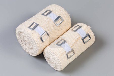Photo for Two modern woven elastic medical bandages different sizes with aluminum stretchable clips rolled into rolls on a gray background - Royalty Free Image