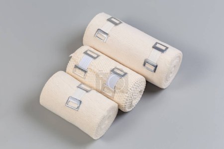 Photo for Several modern woven elastic medical bandages different sizes and fabric structure with aluminum stretchable clips rolled into rolls on a gray background - Royalty Free Image