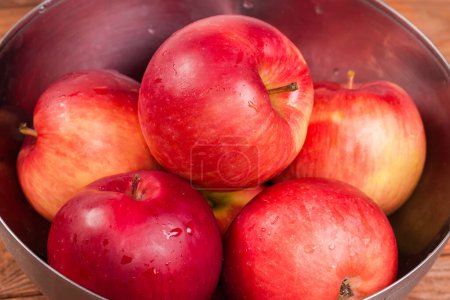 Photo for Washed red apples covered with water drops in the stainless steel kitchen bowl close-up in selective focus - Royalty Free Image