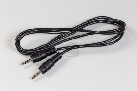 Photo for Rolled up black analog audio cable with stereo connectors mini jack on the edges lies on a gray surface close-up - Royalty Free Image