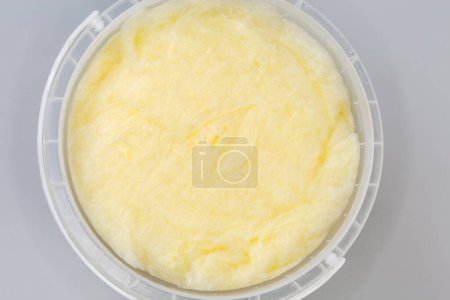Photo for Banana-flavored cotton candy of thick consistency in the open plastic container, top view close-up on a gray background - Royalty Free Image