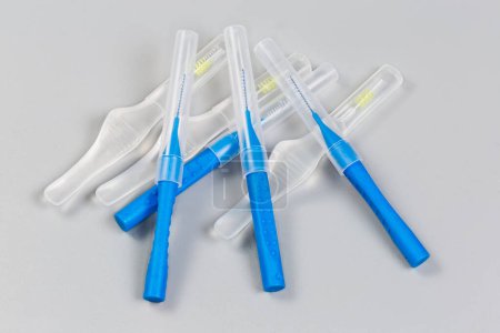 Different disposable interdental brushes covered with caps lie on a gray surface