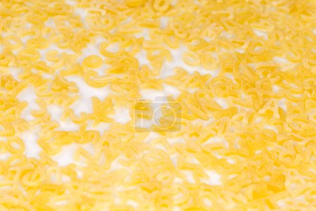 Foto de Pasta cruda en forma de letras mayúsculas del alfabeto inglés y números arábigos vertidos sobre un plato blanco, vista superior de cerca - Imagen libre de derechos