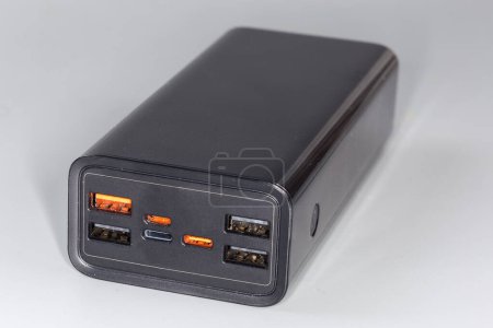 Foto de Banco de energía con puertos USB de entrada y varios puertos USB de salida y otros estándares para la carga portátil de baterías de equipos móviles sobre un fondo gris - Imagen libre de derechos