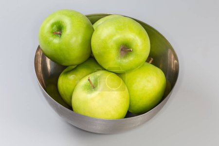 Photo for Whole green apples in the stainless steel kitchen bowl on a gray background - Royalty Free Image