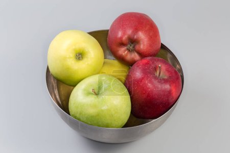 Photo for Whole green, yellow and red apples in the stainless steel kitchen bowl on a gray background - Royalty Free Image