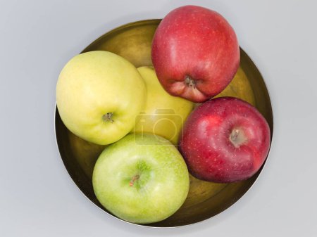 Photo for Whole green, yellow and red apples in the stainless steel kitchen bowl on a gray background, top view - Royalty Free Image