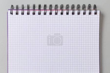 Foto de Hoja en blanco de papel cuadrado de un libro de ejercicios escolares o cuaderno de papel con encuadernación en espiral de alambre negro sobre un fondo gris, vista superior - Imagen libre de derechos