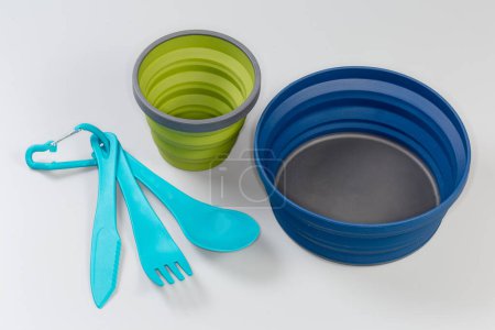 Photo for Camp set of foldable bowl and cup made of durable food-grade flexible thermosilicone, cutlery consisting of food polypropylene knife, fork and spoon on a gray surface - Royalty Free Image