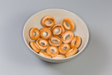 Crunchy ring shaped small cookies, so called sushki laid in one layer in bowl on a gray background