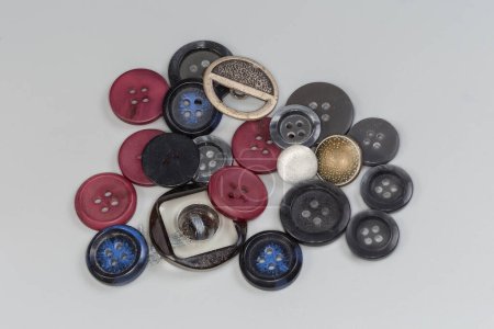 Petit tas de plastique moderne, métal et tissu recouvert de boutons plats à coudre et tige de conception différente sur un fond gris