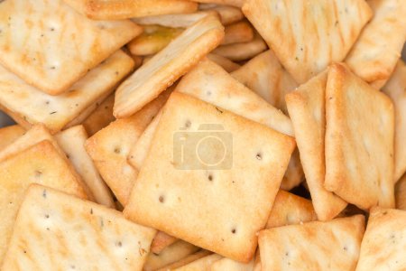 Heap of salty crackers square shape with onion content, top view close-up