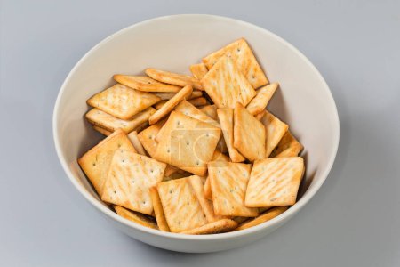 Salzige Cracker mit Zwiebelzusatz bei der Zubereitung in einer Schüssel auf grauem Hintergrund