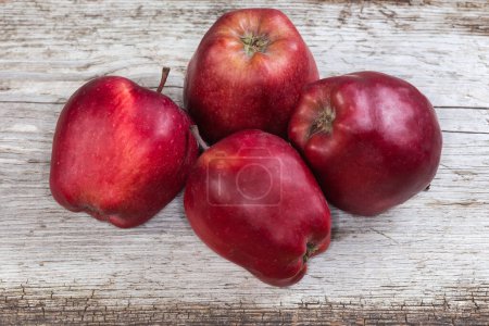 Photo for Several whole dark red apples on an old cracked wooden surface - Royalty Free Image