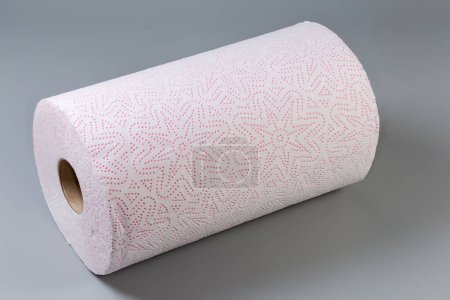 Roll of disposable paper towels with tear-off sheets on a gray surface