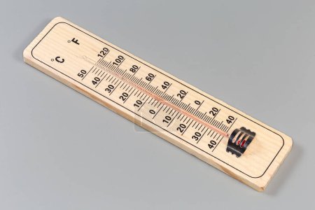 Alcohol thermometer with natural wooden base and double scale of Celsius and Fahrenheit units on a gray background