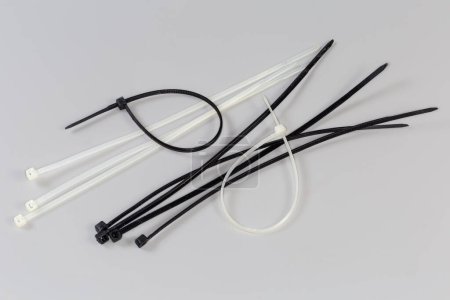 Plusieurs attaches de câbles translucides en nylon à usage unique noir et blanc non fixées sur fond gris