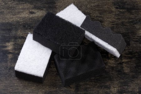 Téléchargez les photos : Plusieurs éponges de nettoyage synthétiques douces de cuisine en noir et blanc avec couche abrasive en uréthane dur sur une surface noire - en image libre de droit
