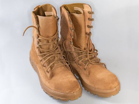 Pair of the beige waterproofed leather summer combat boots on shoelaces on a gray background