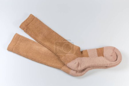 Pair of the beige thick high length military boot socks on a light background