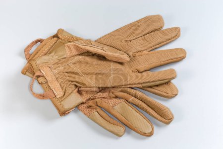 Pair of the beige tactical military gloves made with textile and synthetic leathern on a gray background