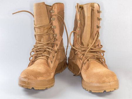 Pair of the beige waterproofed leather summer combat boots on shoelaces on a gray background, front view