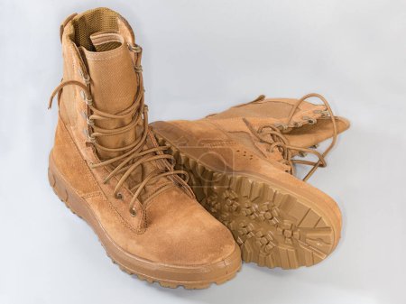 Par de botas de combate de verano de piel beige impermeabilizadas sobre cordones de zapatos sobre fondo gris