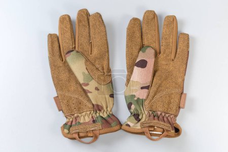 Pair of the green-brown tactical military gloves made with textile and synthetic leathern on a gray background