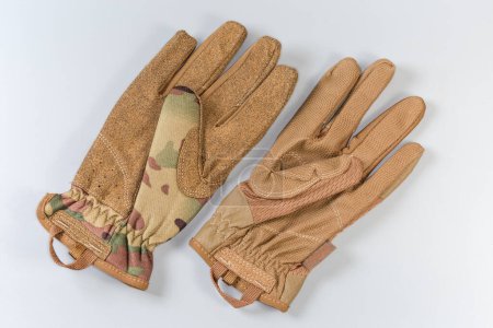 Zwei verschiedene taktische Militärhandschuhe aus Textil und Kunstleder mit Schutzfarbe auf grauem Hintergrund