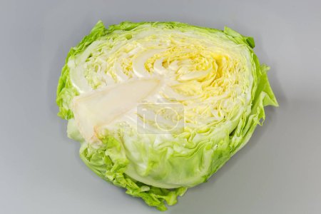 Half the head of young white cabbage on a gray background, close-up