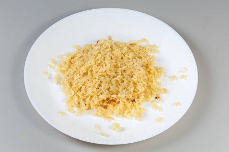 Boiled pasta in shape of the capital letters of English alphabet and Arabic numerals on a white dish on a gray background