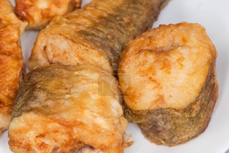 Trozos fritos de merluza hubbsi, o merluza argentina en plato blanco, fragmento de primer plano en enfoque selectivo