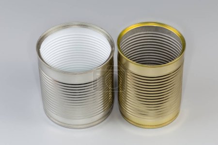 Two open empty tin cans from under a canned food, with white and yellow covering on a gray background
