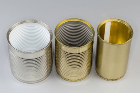Diferentes latas vacías abiertas de debajo de una comida enlatada, con varias cubiertas blancas y amarillas sobre un fondo gris